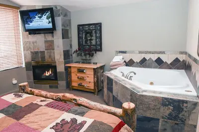 a bathroom with a tub and a tv and a fireplace at Fawn Valley Inn- 103 condo in Estes Park