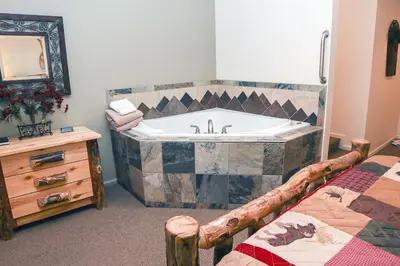 a bathroom with a bath tub with a bed at Fawn Valley Inn- 103 condo in Estes Park