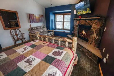 a bedroom with a fireplace and a bed with a quilt at Lazy R Cottages- 18 cabin in Estes Park
