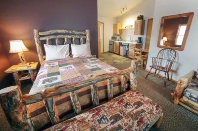 a bedroom with a large bed and a kitchen at Lazy R Cottages- 18 cabin in Estes Park