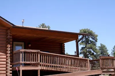 a log cabin with a large wooden deck at Lazy R Cottages- 18 cabin in Estes Park