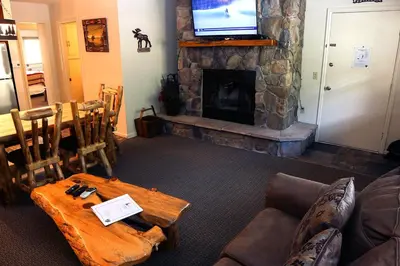 a living room with a fireplace and a table and a television at Fawn Valley Inn- 277 condo in Estes Park