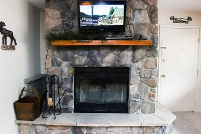 a stone fireplace with a television on top of it at Fawn Valley Inn- 277 condo in Estes Park