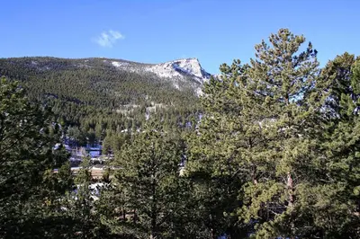 a view of a mountain from behind some trees at Fawn Valley Inn- 277 condo in Estes Park