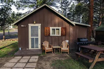 a small cabin with chairs and a table and a grill at Triple R Cottages- 3 cabin in Estes Park