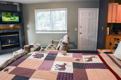 a living room with a quilt on a bed at Fawn Valley Inn- 256 apts in Estes Park