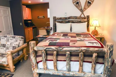 a bedroom with a wooden bed and two chairs at Fawn Valley Inn- 256 apts in Estes Park