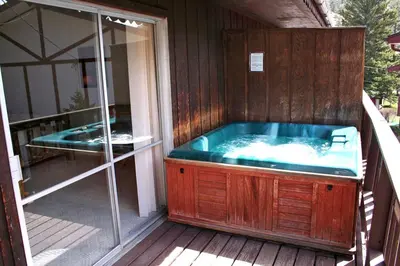 a jacuzzi tub on a deck next to a window at Fawn Valley Inn- 256 apts in Estes Park