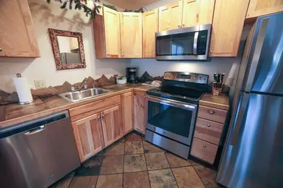 a kitchen with wooden cabinets and a stainless steel refrigerator at Fawn Valley Inn- 267 condo in Estes Park