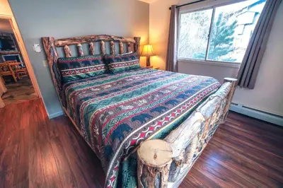 a bedroom with a large bed with a wooden floor at Fawn Valley Inn- 267 condo in Estes Park