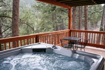 a hot tub on a deck with a table and chairs at Fawn Valley Inn- 267 condo in Estes Park