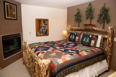 a bedroom with a wooden bed and a fireplace at Lazy R Cottages- 15 cabin in Estes Park