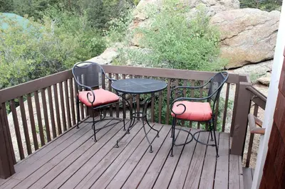 two chairs and a table on a wooden deck at Sunnyside Knoll- 19 apts in Estes Park
