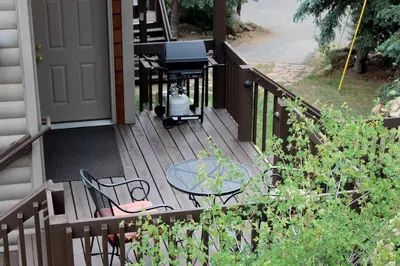 a wooden deck with a table and chairs on it at Sunnyside Knoll- 19 apts in Estes Park
