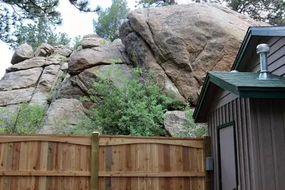 a wooden fence in front of a large rock at Sunnyside Knoll- 11 apts in Estes Park