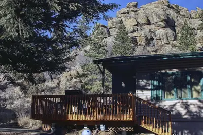 a house with a wooden deck in front of a mountain at Sunnyside Knoll- 16 cabin in Estes Park