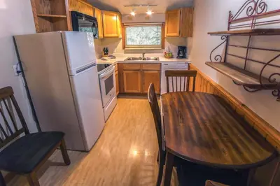 a kitchen with a wooden table and a refrigerator at Sunnyside Knoll- 16 cabin in Estes Park