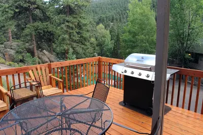 a grill on a wooden deck with a table and a table gmaxwell gmaxwell gmaxwell gmaxwell at Sunnyside Knoll- 15 cabin in Estes Park