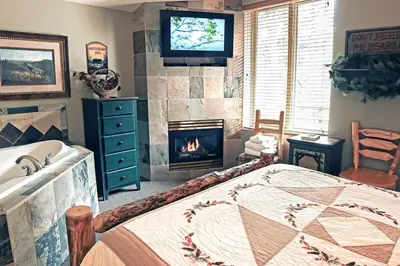 a bedroom with a fireplace and a bed and a television at Fawn Valley Inn- 102 condo in Estes Park