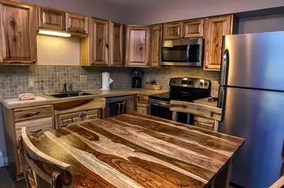 a kitchen with a wooden table and a stainless steel refrigerator at Fawn Valley Inn- 303 apts in Estes Park