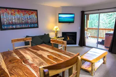 a living room with a wooden table and a fireplace at Fawn Valley Inn- 303 apts in Estes Park