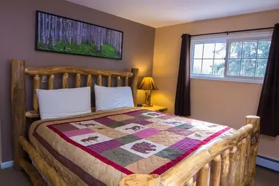a bedroom with a wooden bed with a quilt on it at Fawn Valley Inn- 303 apts in Estes Park