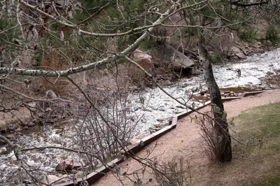 a river with snow on the ground and a wooden bridge at Fawn Valley Inn- 240 condo in Estes Park