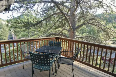 a table and chairs on a deck with a tree at Fawn Valley Inn- 269 condo in Estes Park