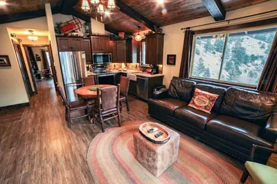 a living room with a leather couch and a kitchen at Fawn Valley Inn- 269 condo in Estes Park