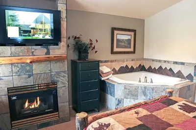 a bathroom with a tub and a television and a fireplace at Fawn Valley Inn- 105 condo in Estes Park