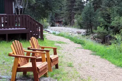 two wooden chairs sitting on a path next to a house at Fawn Valley Inn- 157 cabin in Estes Park