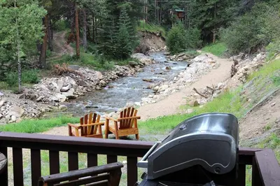 a view of a river from a deck with two chairs at Fawn Valley Inn- 157 cabin in Estes Park