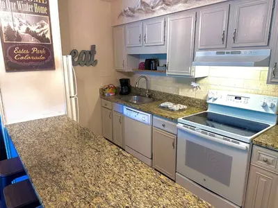 a kitchen with white cabinets and a stove top oven at Fawn Valley Inn- 288 condo in Estes Park