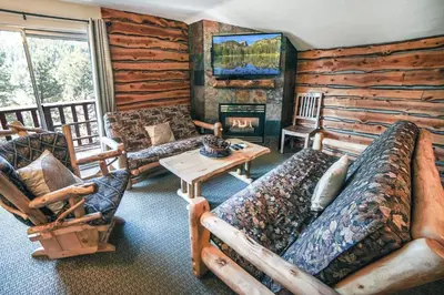 a living room with couches and a fireplace in a log cabin at Fawn Valley Inn- 279 condo in Estes Park
