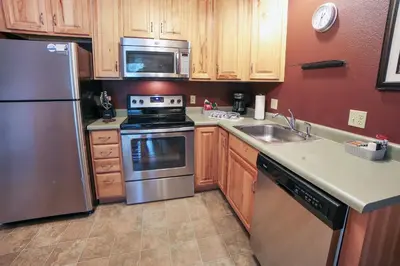 a kitchen with stainless steel appliances and wooden cabinets at Fawn Valley Inn- 298 condo in Estes Park