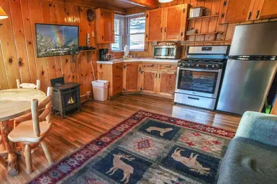 a kitchen with wooden cabinets and a table and a refrigerator at Lazy R Cottages- 3 cabin in Estes Park