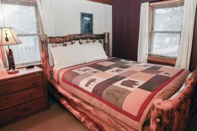 a bedroom with a large bed with a wooden frame at Lazy R Cottages- 3 cabin in Estes Park