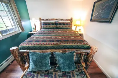 a bedroom with a large bed with two chairs at Fawn Valley Inn- 205 condo in Estes Park