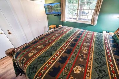 a bedroom with a bed with a colorful blanket on it at Fawn Valley Inn- 205 condo in Estes Park