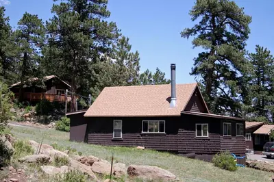 a black house on a hill with a house at Lazy R Cottages- 6 cabin in Estes Park