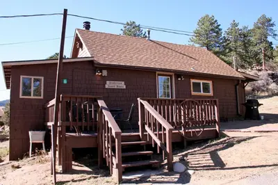 a small house with two wooden stairs in front of it at Lazy R Cottages- 6 cabin in Estes Park