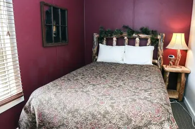 a bedroom with a large bed with purple walls at Lazy R Cottages- 6 cabin in Estes Park