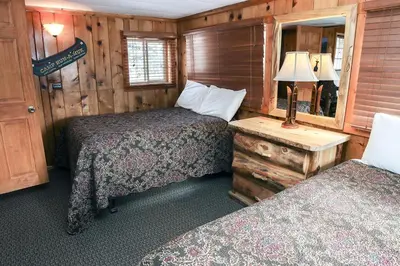 a bedroom with two beds and a table with a mirror at Lazy R Cottages- 6 cabin in Estes Park