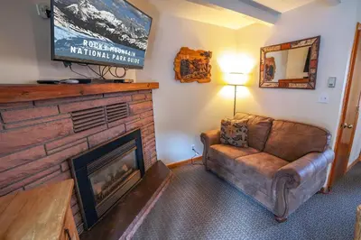 a living room with a couch and a flat screen tv at Sunnyside Knoll- 14 studio in Estes Park