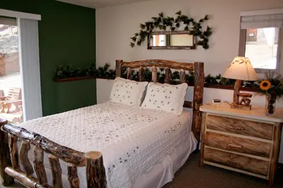 a bedroom with a wooden bed and a table with a lamp at Lazy R Cottages- 16B cabin in Estes Park