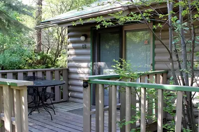 a wooden deck with a table and a house at Sunnyside Knoll- 12 apts in Estes Park
