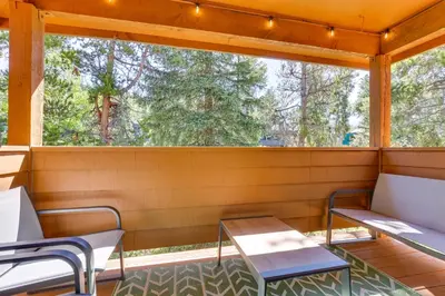 a screened porch with two chairs and a table at Winter Park Condo with Private Balcony Near Skiing! in Winter Park