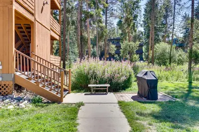 a garden with a bench and a trashcan next to a house at Winter Park Condo with Private Balcony Near Skiing! in Winter Park