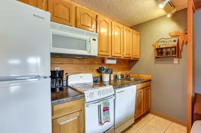 a kitchen with wooden cabinets and a white stove top oven at 2 Mi to Granby Ranch Granby Vacation Rental! in Granby