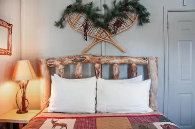 a bed with white pillows and a christmasreath on the wall at Fawn Valley Inn- Cabana apts in Estes Park
